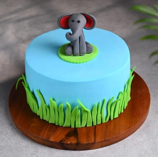 A jungle-themed birthday cake with a cute smiling elephant, leaves, and animal-inspired decorations.