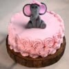 Fondant cake with a smiling baby elephant topper and pastel decorations, ideal for baby showers or 1st birthdays.