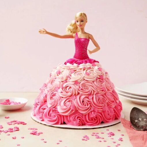 Barbie doll cake featuring a cascading pink‑rose buttercream gown with delicate fondant petals and pearl accents.