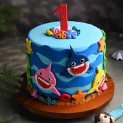 Colorful fondant cake featuring Baby Shark family characters, perfect for kids' birthday parties and themed celebrations.