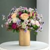 Golden vase filled with a vibrant mix of fresh flowers in a luxurious arrangement.