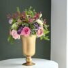 Golden vase filled with a vibrant mix of fresh, opulent flowers.