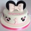 Cute pink Minnie Mouse fondant cake with polka dots and bow design for a themed birthday celebration.