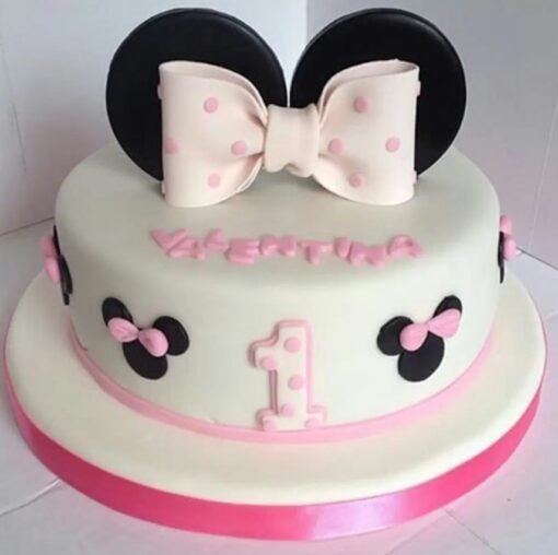Cute pink Minnie Mouse fondant cake with polka dots and bow design for a themed birthday celebration.