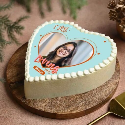 Heart-shaped cake with personalized edible photo on top, decorated beautifully.
