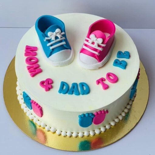 Pink and blue baby theme cake with fondant baby shoes and pastel decorations.