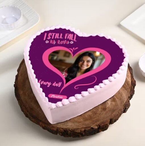 Heart-shaped photo cake with Valentine’s Day decorations and personalized image on top.