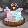 Blush pink and pastel blue baby shower cake decorated with baby-themed fondant toppers.