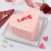 Heart-shaped cake in pastel pink with delicate decorations and soft buttercream finish.
