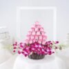Basket arrangement of pink roses and purple orchids with green fillers.
