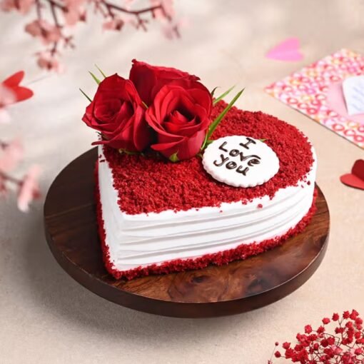 Heart‑shaped red velvet cake fully piped with red buttercream roses and a golden “I Love You” topper.