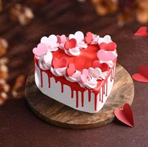 Heart‑shaped red velvet Valentine’s cake with cream‑cheese frosting, red rosettes, and a gold “Sweetheart” topper.