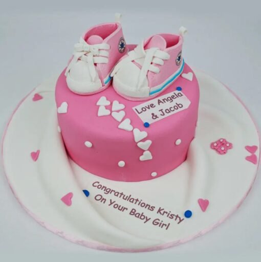 It’s A Girl Sneaker Cake with pink baby shoe toppers and pastel-themed design for baby shower celebrations.