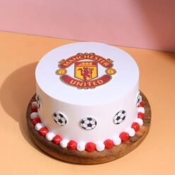 Football Team Manchester United Cake featuring red and black design, club logo, and football decorations.