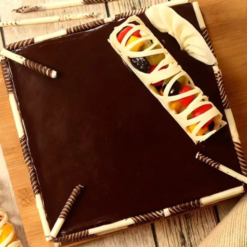 Chocolate truffle cake topped with fresh fruits and glossy glaze